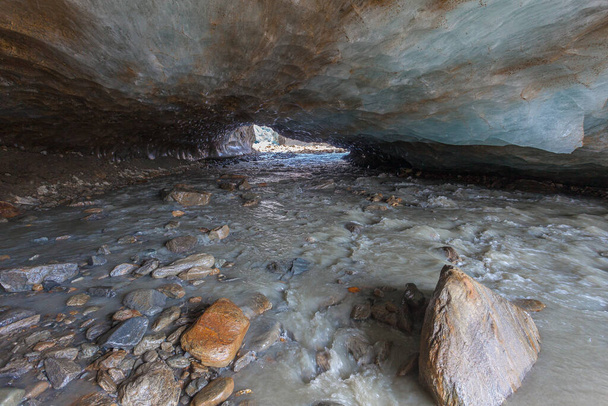 Vchod do ledové jeskyně vytesané do ledovce Vallelunga protékající potokem. Ledovec je v rychlém ústupu způsobeném globálním oteplováním, Alto Adige, Itálie - Fotografie, Obrázek