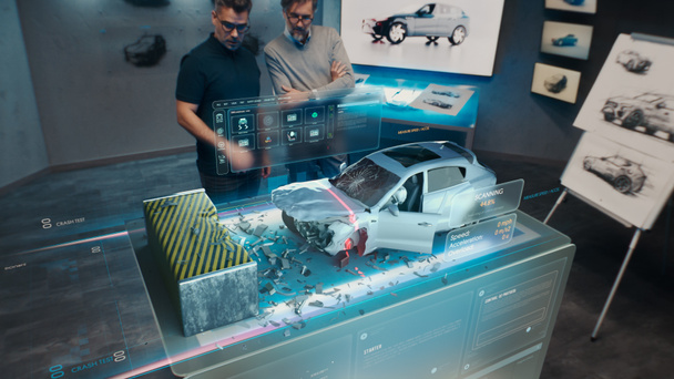 Два инженера Разработчика, стоящие в конструкторской студии рядом с футуристическим голографическим столом и делают тест в 3D симуляторе автокатастрофы, который имитирует дорожно-транспортное происшествие проверить безопасность - Фото, изображение