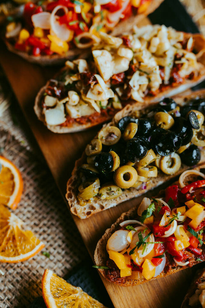 Brushetta zestaw na imprezę, Różnorodność małych kanapek z, grzyby, pomidory, ser parmezan, świeża bazylia i balsamiczny na rustykalnym drewnianej desce na ciemnym tle - Zdjęcie, obraz