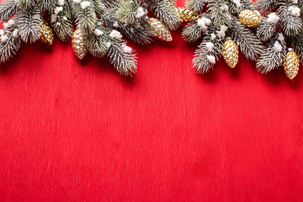 Border from branches of fir tree and decorative golden cones on  red paper textured background. Top view. Christmas, New Tear holidays concept.  Place for text. - Foto, imagen