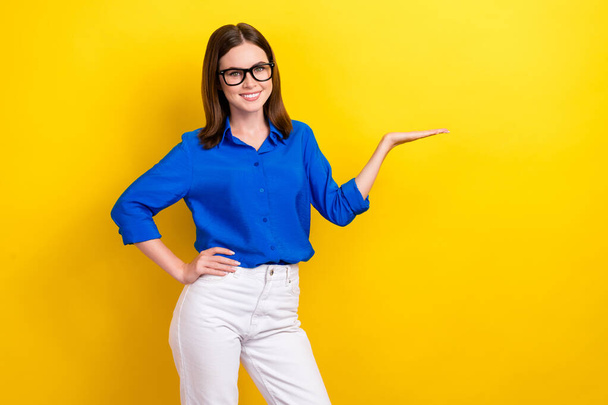 Photo of smiling cheerful good mood businesswoman wear blue shirt hold palm new it project for sale isolated on yellow color background. - Foto, Imagem