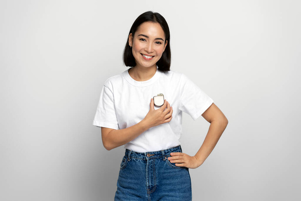Pozytywny azjatycki kobieta demonstruje Implantable cardioverter defibrylator (ICD) na rękach podczas patrząc w aparat z przyjemnym uśmiechem. Opieka zdrowotna i koncepcja serca  - Zdjęcie, obraz