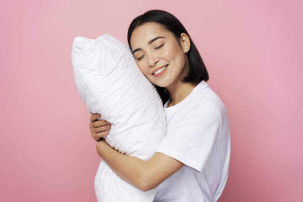 Foto retrato de una hermosa chica abrazando almohada con los ojos cerrados aislados sobre fondo de color rosa. Concepto para dormir  - Foto, imagen