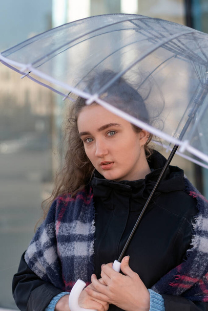 Retrato de chica triste en abrigo de otoño bajo paraguas transparente. Encantadora joven rizado mujer uso paraguas fuera en día lluvioso - Foto, Imagen