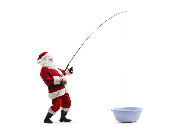 Full length profile shot of santa claus fishing in a washing basin isolated on white background - Foto, Imagen