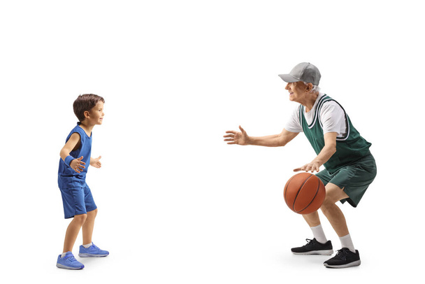 Full length profil záběr dítěte hrající basketbal se starším mužem izolované na bílém pozadí - Fotografie, Obrázek