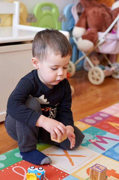 cute young boy playing with toys in the baby room at home - Photo, Image