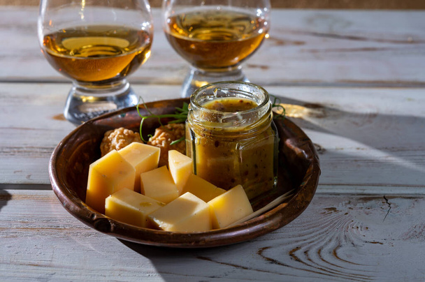 Juuston maistelua, pieniä paloja vanhaa hollantilaista kovaa juustoa ja kulhoa kotitekoisella tilli-sinappikastikkeella, lähikuva - Valokuva, kuva