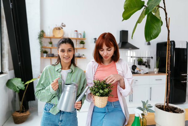 Young women with a watering can and a houseplant in a pot - Photo, Image