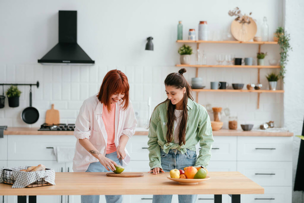 Young women cutting citrus fruits to make fresh juice in kitchen - Fotoğraf, Görsel