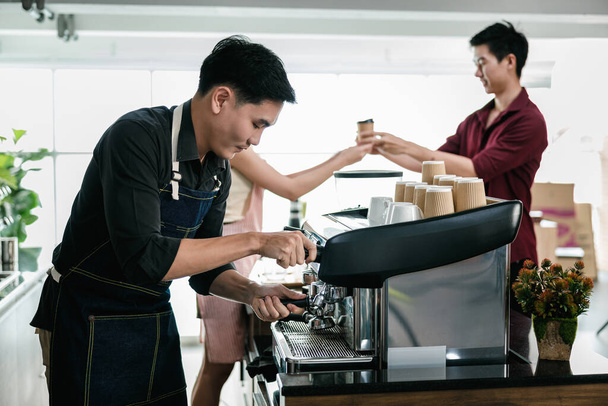 asian man bartender mixing and pouring coffee into cup from coffee machine at counter in small coffee shop business stratup concept, cinema film tone process - Photo, image