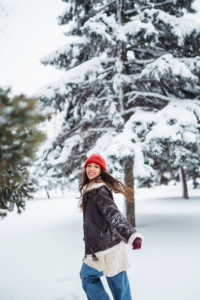 A fiatal nő nevet és havat dob egy téli havas parkban. Ünnepek, pihenés, utazás. - Fotó, kép