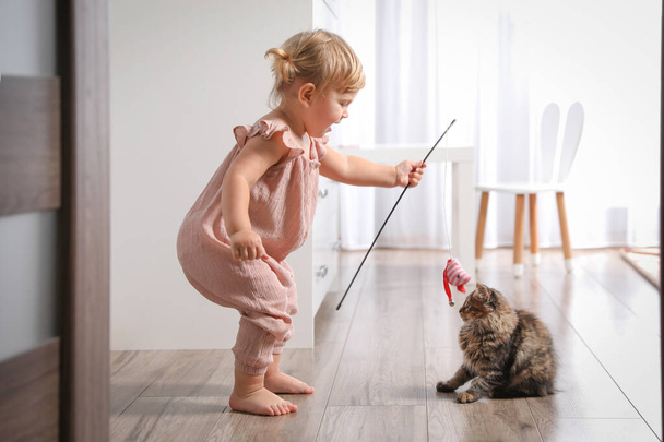 Милый маленький ребенок играет с очаровательным домашним животным дома - Фото, изображение