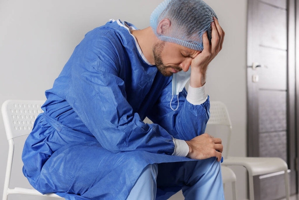 Exhausted doctor sitting on chair in hospital corridor - Photo, image