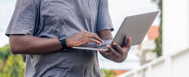 Ritratto a mano di uno sviluppatore web africano che lavora con il suo computer portatile, con uno smartwatch. - Foto, immagini