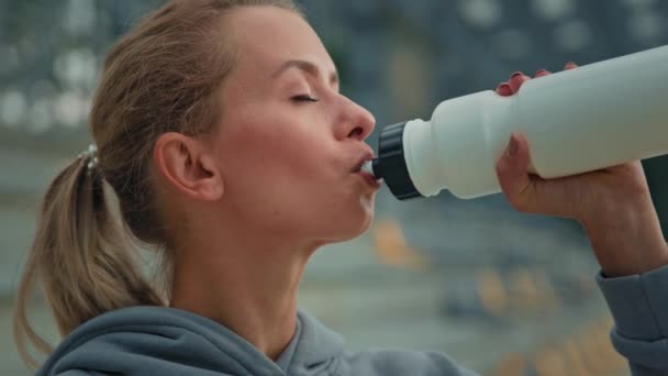Healthy woman athletic sportswoman caucasian girl runner jogger athlete female drink fresh water cold water sportive nourishment protein for energy lifestyle hydration body after sport on city stadium - Footage, Video