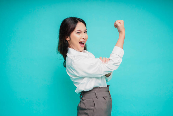 Excited Asian woman wearing a white shirt showing strong gesture by lifting her arms and muscles smiling proudly - Valokuva, kuva