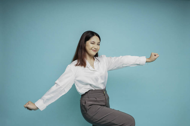 A young Asian woman with a happy successful expression wearing white shirt isolated by blue background - Foto, Imagen