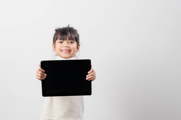Asijské holčička držení a používání digitálního tabletu na bílém pozadí studia, volné místo pro kopírování - Fotografie, Obrázek