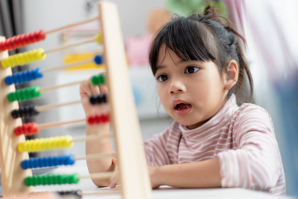 Una giovane ragazza asiatica carina sta usando l'abaco con perline colorate per imparare a contare a casa - Foto, immagini