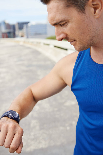 Ready to beat his time. Cropped image of a male runner looking at his watch before a run - Foto, Bild