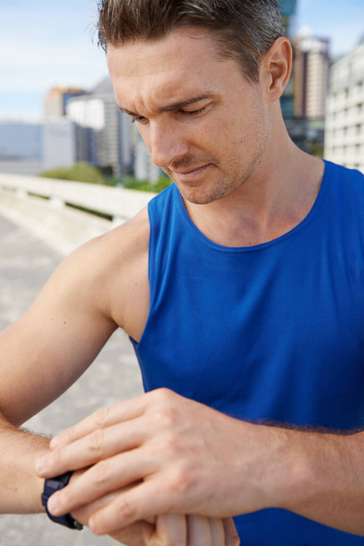 Time trial day. Cropped image of a male runner setting his watch before a run - Zdjęcie, obraz
