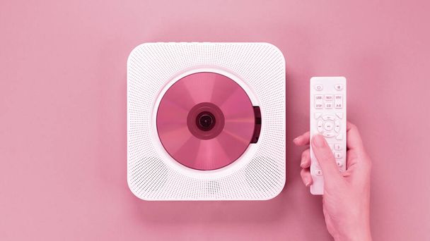 Color of year 2023 Viva Magenta. Image with hand holding controller for stylish portable compact CD player with disc is toned in pantone color. New Fashion colour. Retro vintage. Top view, copy space - Photo, image