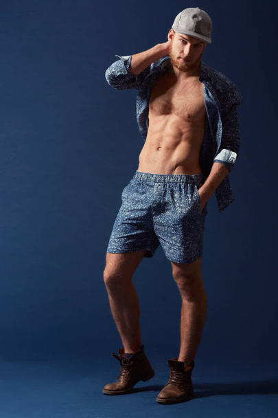 Striking a pose. A muscular young man with an open shirt and unique fashion sense - 写真・画像