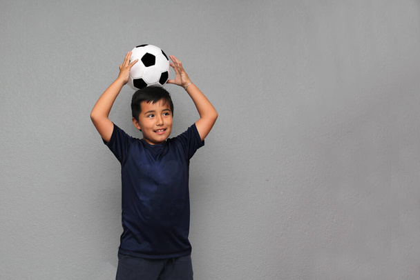 Hispanic Latino 8-year-old boy plays with a soccer ball very excited that he is going to see the football game and wants to see his team win - Foto, imagen