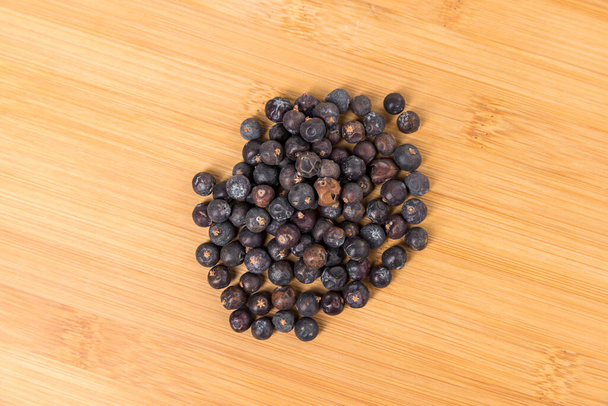 Juniper berries in a pile on a wood cutting board top down - Valokuva, kuva