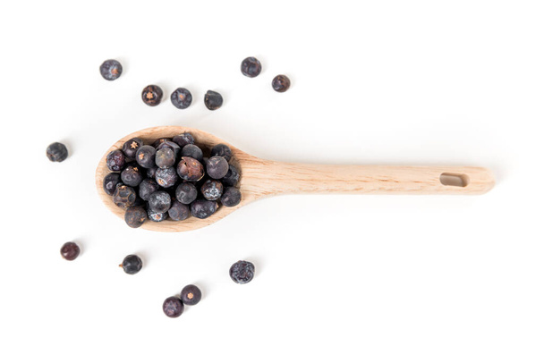 Juniper berries scattered around a wood spoon isolated over white top down - Foto, Imagem