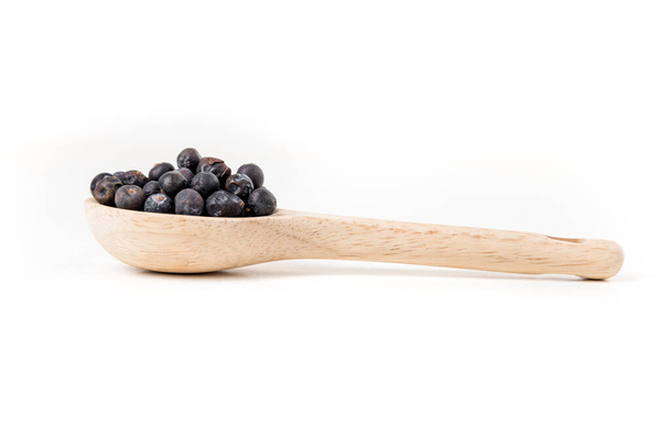 Juniper berries in a wood spoon isolated over white side view - Valokuva, kuva