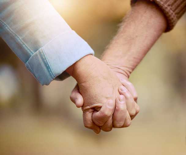 Älteres Paar, Händchen haltend und in der Natur spazierend, um sich auf dem Land für Liebe, Fürsorge und Zuneigung zu verbinden. Ruhestand, die Hände eines älteren Ehepaares in einer liebevollen, fürsorglichen Beziehung. - Foto, Bild