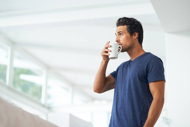 Sipping on a cup of coffee. A handsome young man drinking a cup of coffee at home - copyspace - Photo, Image