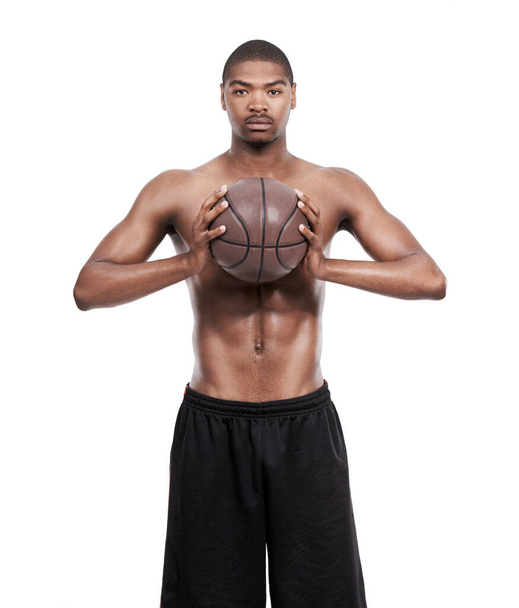 Бросаю тебе пропуск. Портрет красивого молодого баскетболиста, стоящего без рубашки в студии - Фото, изображение
