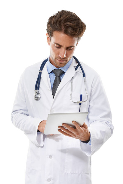 Keeping abreast of medicine with new technology. a serious-looking doctor looking at a clipboard he is holding - Fotó, kép