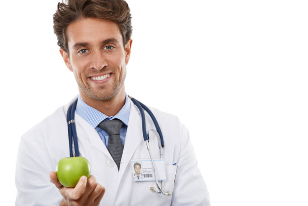 It really will keep me away. Studio portrait of a handsome young doctor holding an apple up to the camera - Foto, imagen