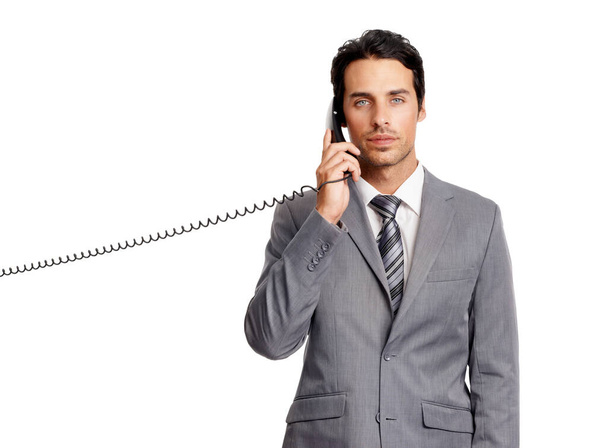 Straight-faced conversation. A handsome young businessman taking a call on a landline -isolated - 写真・画像