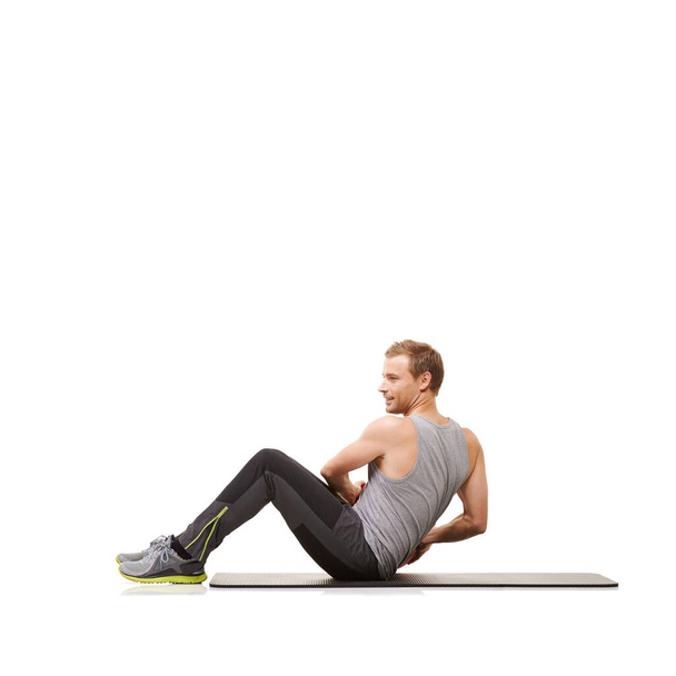 Ponerse en forma para un verano sin camisa. Un joven haciendo ejercicio con una pelota de medicina sobre un fondo blanco - Foto, imagen