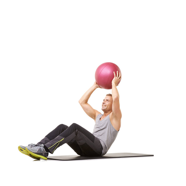 Dándole a sus músculos el ejercicio que necesitan. Un joven haciendo ejercicio con una pelota de medicina sobre un fondo blanco - Foto, imagen