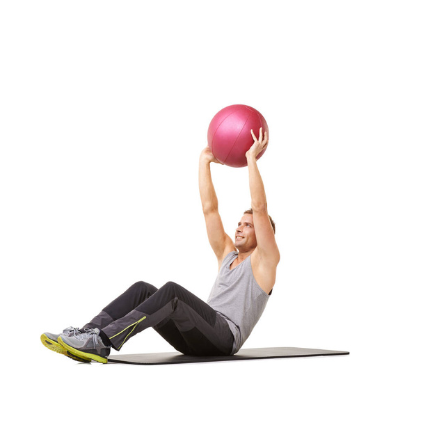 Strengthening his core. A young man working out with a medicine ball on a white background - Fotó, kép