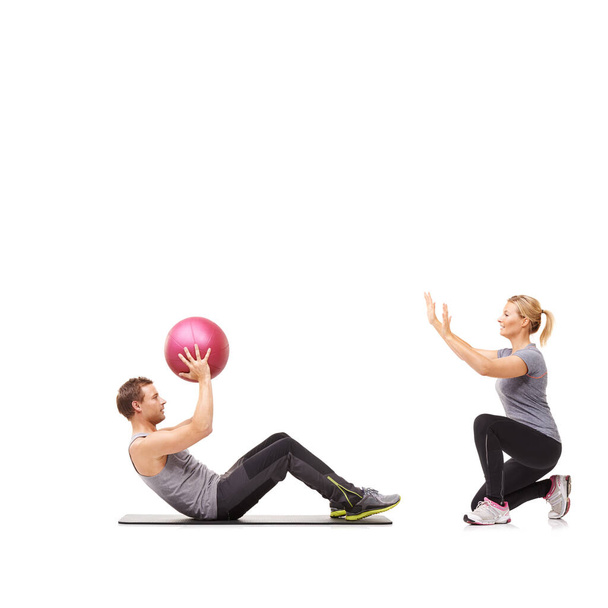 Bewegung macht Spaß. Ein Mann und eine Frau, die ihren Bauch trainieren, indem sie einander einen Medizinball reichen - Foto, Bild