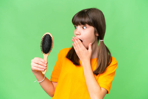 Little caucasian girl with hair comb over isolated background with surprise and shocked facial expression - Foto, immagini