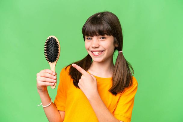 Little caucasian girl with hair comb over isolated background and pointing it - Photo, Image