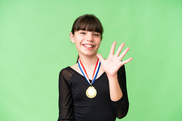 Little caucasian girl with medals over isolated background counting five with fingers - Photo, Image