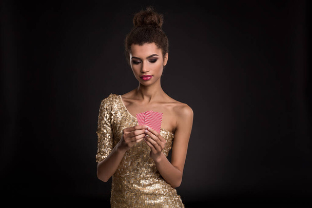 Mulher vencedora - Jovem mulher em um vestido de ouro elegante segurando duas cartas, um poker de combinação de cartas ases. Estúdio filmado em fundo preto. Emoções
 - Foto, Imagem