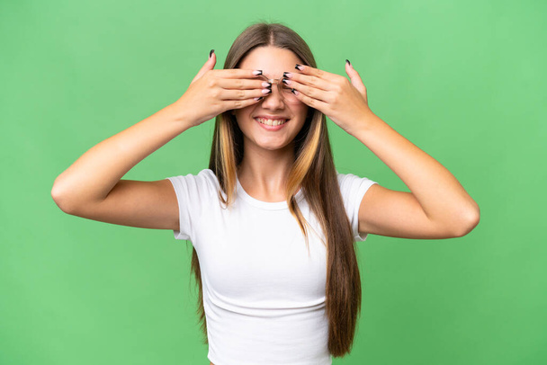 Adolescente caucasiana menina sobre fundo isolado cobrindo os olhos por mãos e sorrindo - Foto, Imagem