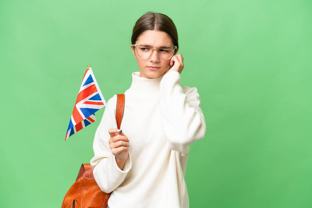 Teenager student caucasian girl holding an United Kingdom flag over isolated background frustrated and covering ears - Foto, Imagem