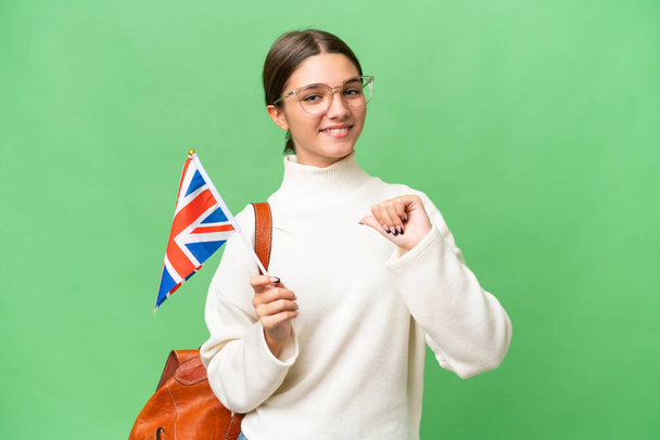 Adolescente estudante caucasiano menina segurando uma bandeira do Reino Unido sobre fundo isolado orgulhoso e auto-satisfeito - Foto, Imagem