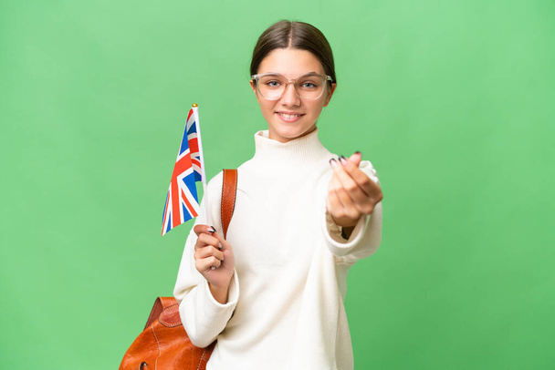 Teenager Student kaukasischen Mädchen hält eine britische Flagge über isoliertem Hintergrund machen Geld Geste - Foto, Bild